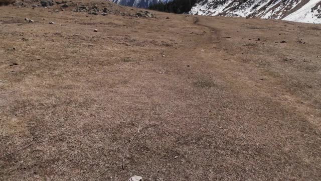 低空飞过一个山谷，有一条小路，石头落在山上。鸟瞰图视频素材