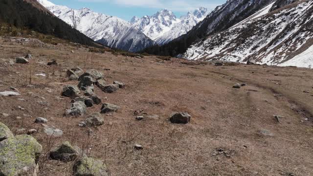 低空飞过一个山谷，有一条小路，石头落在山上。鸟瞰图视频素材