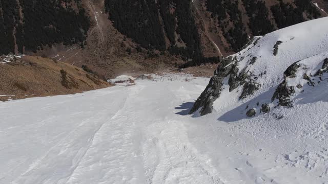 鸟瞰图被雪覆盖的陡峭山坡。狭窄的颜色为极端免费乘车和偏僻的高山滑雪视频素材