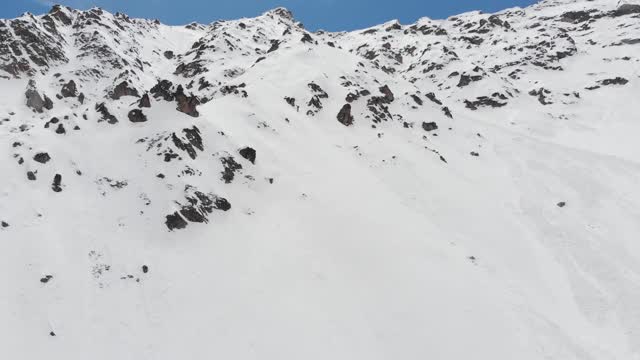 鸟瞰图被雪覆盖的陡峭山坡。狭窄的颜色为极端免费乘车和偏僻的高山滑雪视频素材