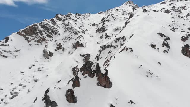 鸟瞰图被雪覆盖的陡峭山坡。狭窄的颜色为极端免费乘车和偏僻的高山滑雪视频素材