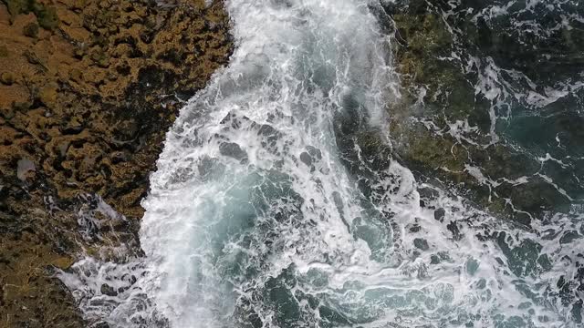 碧绿的海水在岩石海岸上波涛起伏。航拍慢动作视频。视频素材