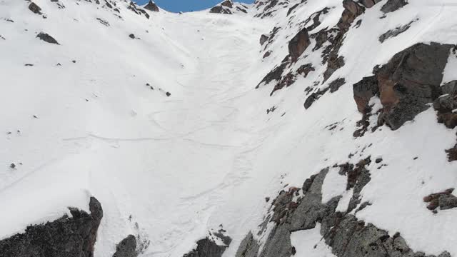 鸟瞰图被雪覆盖的陡峭山坡。狭窄的颜色为极端免费乘车和偏僻的高山滑雪视频素材