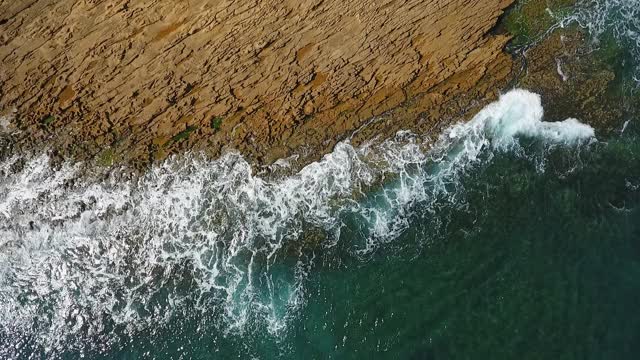 怀旧的航空视频，在缓慢的动作的海洋，波浪平稳地滚在岩石海岸的太平洋大西洋。视频素材