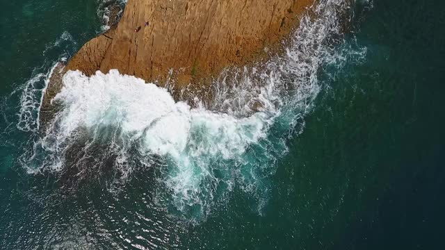 怀旧的航空视频，在缓慢的动作的海洋，波浪平稳地滚在岩石海岸的太平洋大西洋。视频素材