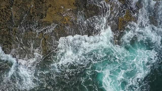 怀旧的航空视频，在缓慢的动作的海洋，波浪平稳地滚在岩石海岸的太平洋大西洋。视频素材