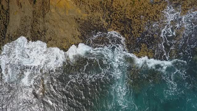 怀旧的航空视频，在缓慢的动作的海洋，波浪平稳地滚在岩石海岸的太平洋大西洋。视频素材