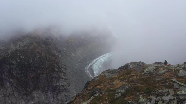 无人机拍摄的两名跑步者跑上一座俯瞰山谷的山的边缘视频素材