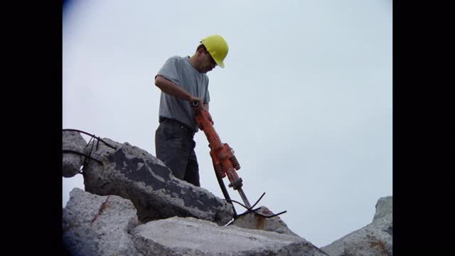 倾斜拍摄建筑工人在工地用手提钻打破水泥视频素材