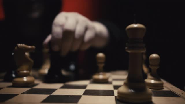 在国际象棋比赛中，穿帽衫的人移动白方王后击败对手的白方国王。视频素材