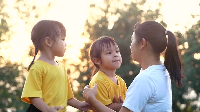 快乐的母亲拥抱她的小女儿与微笑在草坪夏季公园。全家人一起度假。视频素材