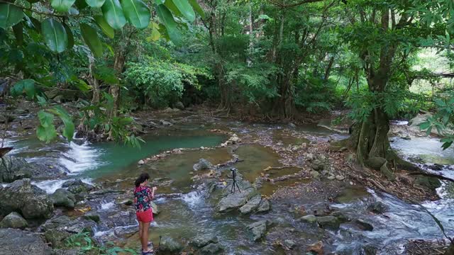 冒险旅行摄影师的概念亚洲女人捕捉美丽的瀑布视频素材