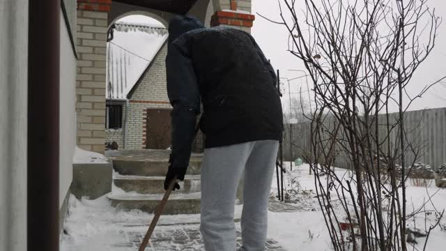 在暴风雪中，人们正在楼梯上铲雪。小路、道路和后院覆盖着积雪。降雪视频素材