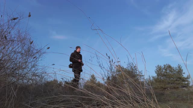 时光流逝的年轻男子摄影师去森林与相机的天空背景视频素材