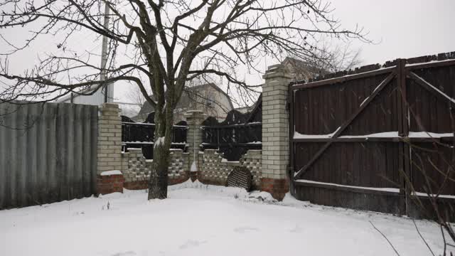 在冬季的暴风雪中，一名年轻人正在后院用铲子清理积雪。男正在房子附近铲雪视频素材