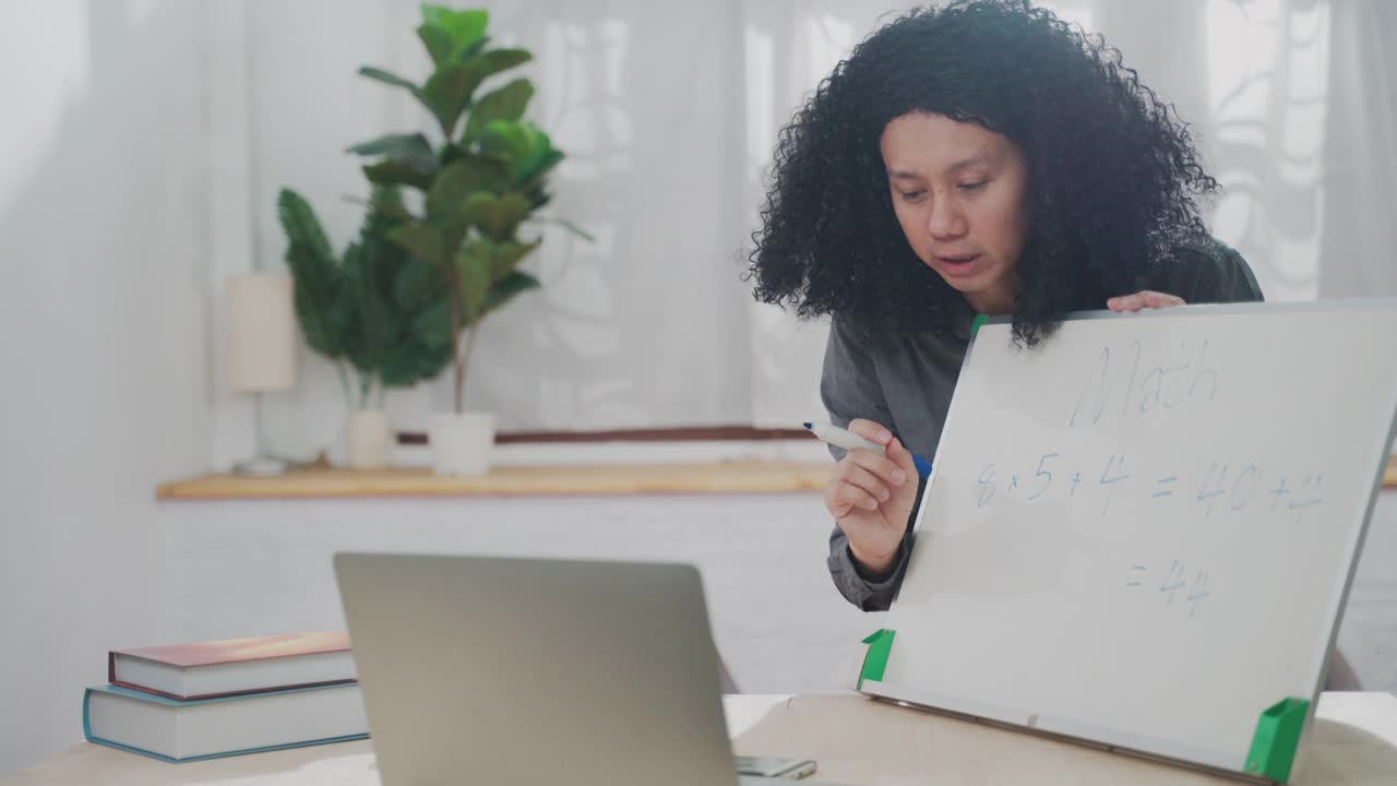 年轻的教师正在使用白板进行在线教学，并通过视频电话与学生交谈视频素材