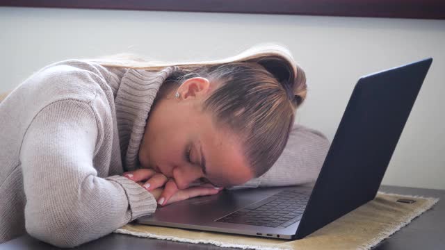 疲惫的年轻女子睡在笔记本电脑上视频素材