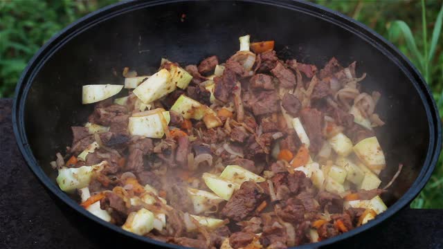 肉与洋葱和西葫芦炖在一个大锅里。在菜中加入黄、红、绿等多种颜色的辣椒。烹饪传统亚洲食物- lagman视频下载