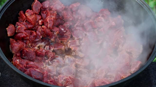 东方菜肴的烹饪过程。红肉在一个大锅里用油煮沸和炖。大型传统亚洲锅在明火上，称为喀山视频下载