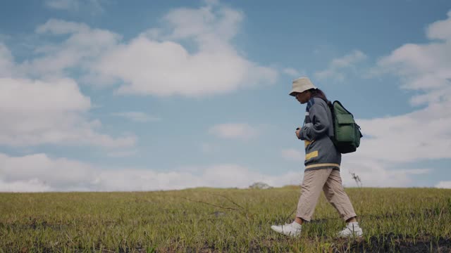 年轻的女性徒步旅行者在草地上行走视频素材