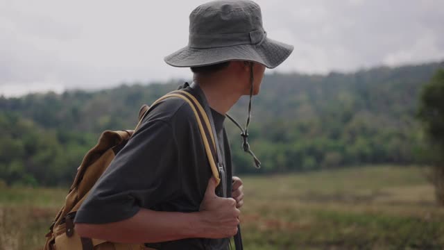 一位男性徒步旅行者在乡间徒步旅行的侧面照片视频素材