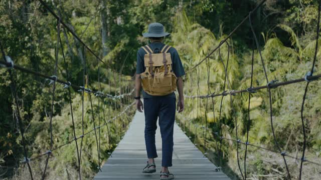 年轻的男性探险家走在森林里的索桥上视频素材