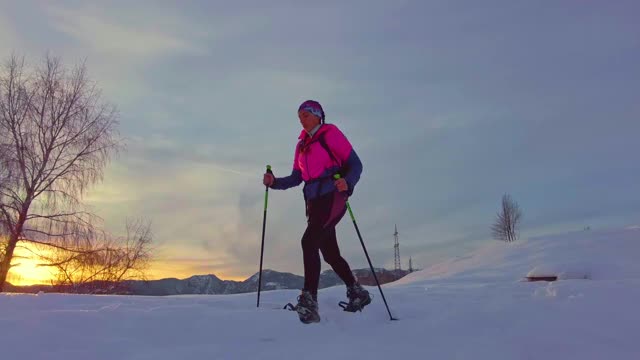 年轻的运动女子在雪地里穿着雪鞋下坡视频素材