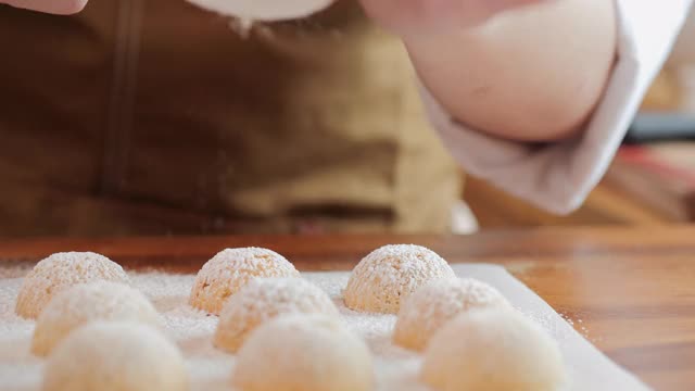 将糖粉撒在厨房木桌上的新鲜黄油饼干上。饼干。视频素材