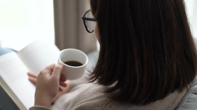 女人在放松的时候在家看书喝咖啡视频素材