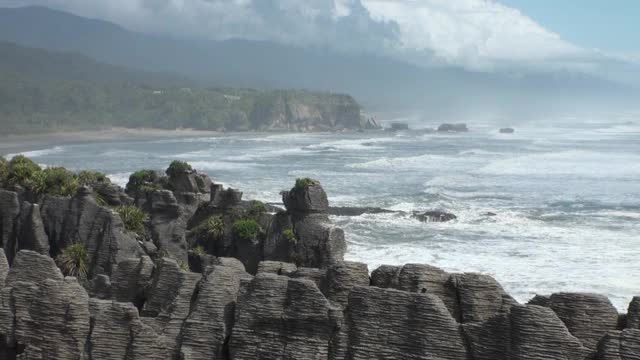 海浪在岩石海岸和山脉新西兰。视频素材