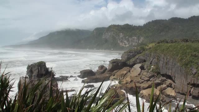 海浪在岩石海岸和山脉新西兰。视频素材