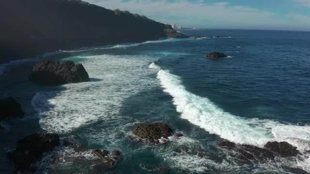 鸟瞰图海浪打破在海滩附近的黑色岩石。海浪对危险的石头鸟瞰图。视频素材