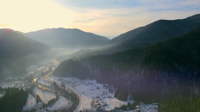 冬季日出的风景在冬天的山。山谷里的山上覆盖着白雪和薄雾视频素材