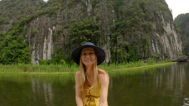 在越南北部的旅游胜地宁平，一名年轻女子在船上在壮观的石灰岩中漂流。去越南旅游的概念视频素材