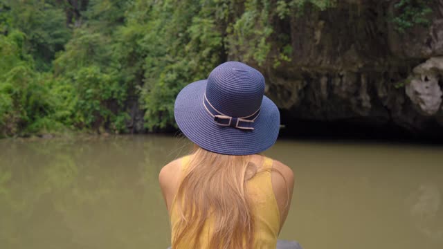 在越南北部的旅游胜地宁平，一名年轻女子在一艘船上在岩石中漂流。去越南旅游的概念视频素材