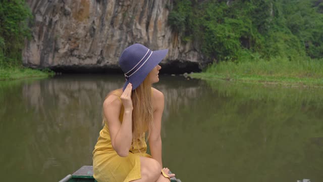 在越南北部的旅游胜地宁平，一名年轻女子在一艘船上在岩石中漂流。去越南旅游的概念视频素材