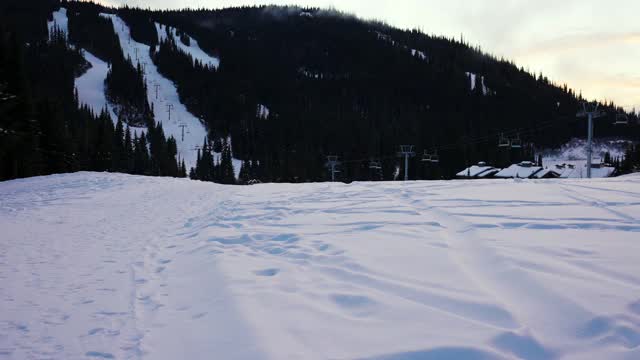 日落时分，白雪覆盖的地面和树木上空无一人的缆车升降椅视频下载