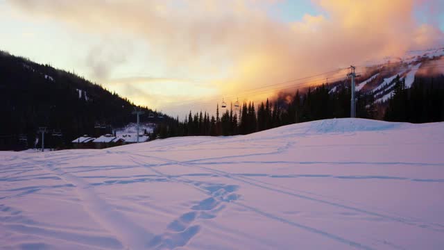 日落时分，白雪覆盖的地面和树木上空无一人的缆车升降椅视频下载