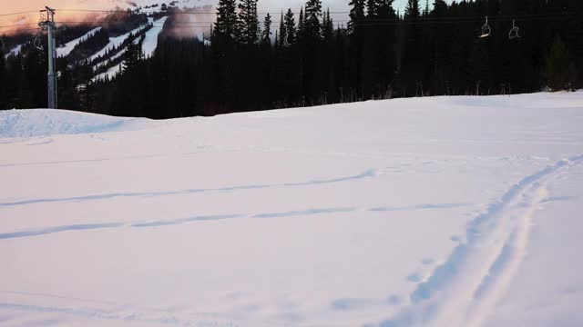 日落时分，白雪覆盖的地面和树木上空无一人的缆车升降椅视频下载