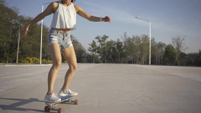 亚洲妇女在美丽的夏天在户外冲浪或滑冰。快乐的年轻女子早上在公园玩冲浪滑冰。视频素材