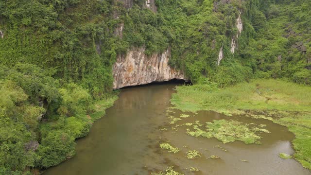 这是越南北部著名的旅游景点宁平地区美丽的石灰岩山脉的航拍照片。去越南旅游的概念。山洞的入口，由河流形成的穿过山的山洞的入口视频素材