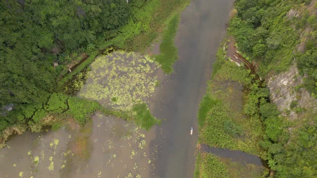 这是越南北部著名的旅游景点宁平地区美丽的石灰岩山脉的航拍照片。去越南旅游的概念。一个当地人在船上顺流而下视频素材