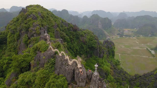 在越南北部的旅游目的地宁平，一名游客在大理石山，Mua洞山山顶的龙纪念碑上航拍。去越南旅游的概念视频素材