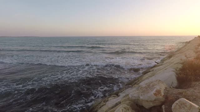 岩石海岸的波浪在大海和日落视频素材