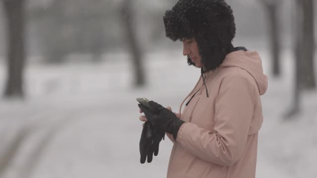 一个女人一边在下雪一边打电话视频素材