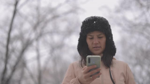 一个女人在冬天走在人行道上打电话视频素材