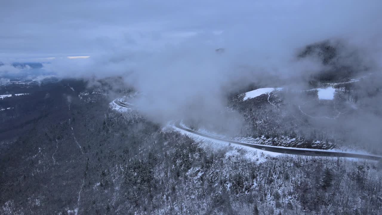 无人机拍摄的雪山高速公路上穿越云层的画面视频素材