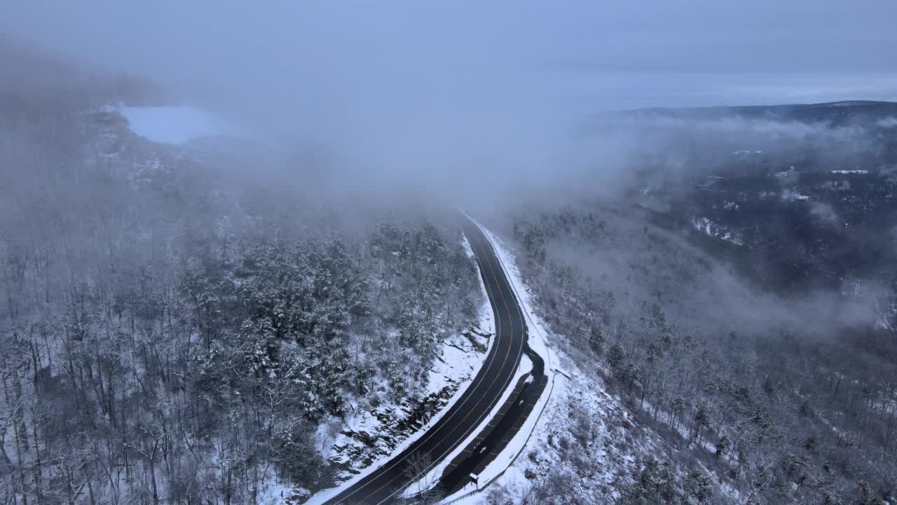 无人机拍摄的雪山高速公路上穿越云层的画面视频素材