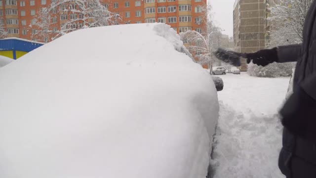 一位妇女用刷子清理汽车上的积雪。视频素材