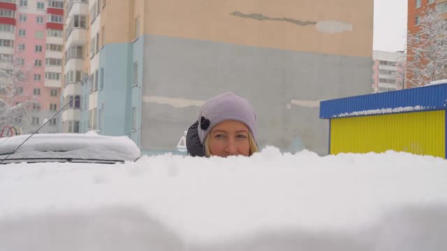 一位妇女用刷子清理汽车上的积雪。视频素材